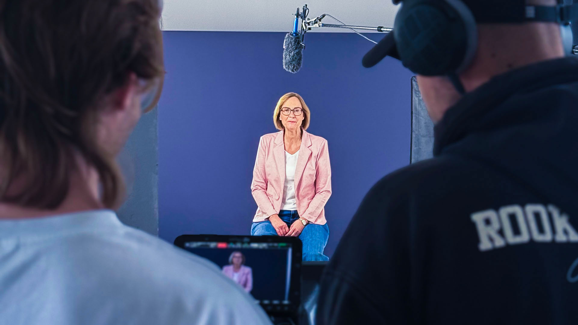Kamerateam filmt Sprecherin vor blauem Hintergrund.