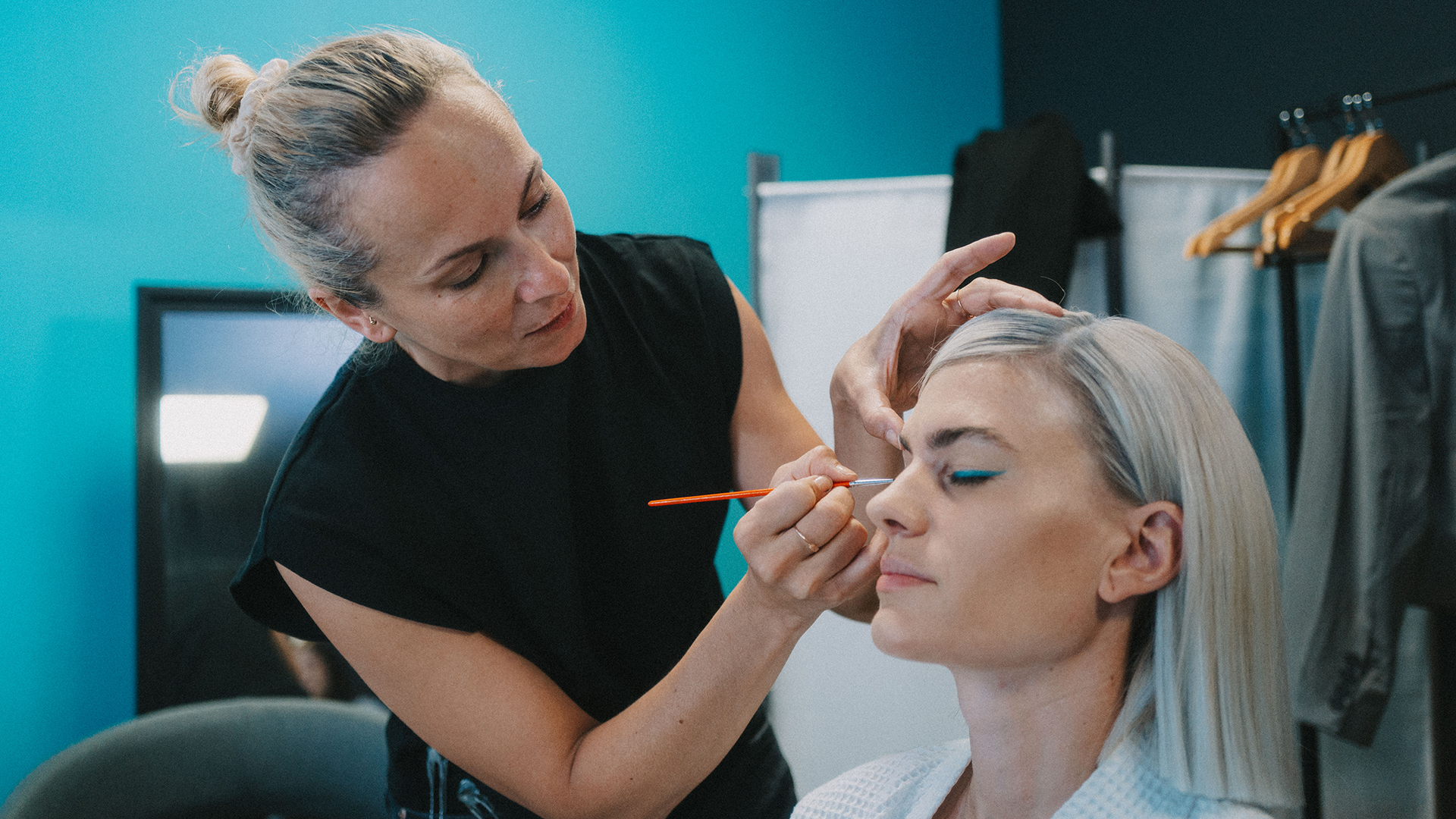 Make-up Artist trägt einer Frau Lidschatten im Studio auf.