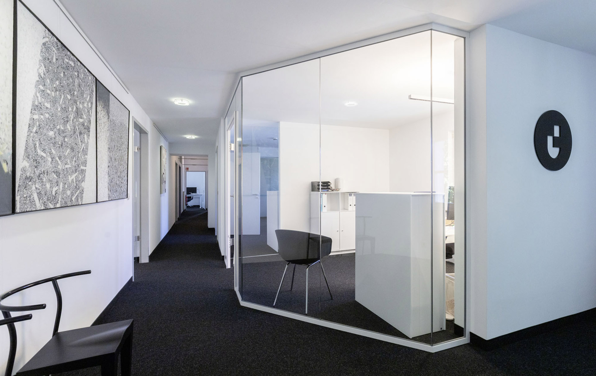 Modern office corridor with a glass meeting room and minimalist interior.