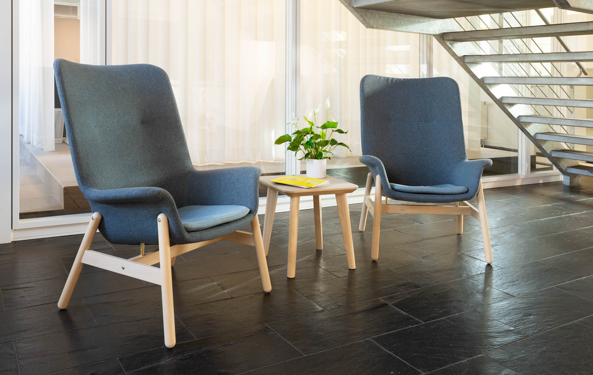 Bright lounge area with two modern armchairs and a small side table.